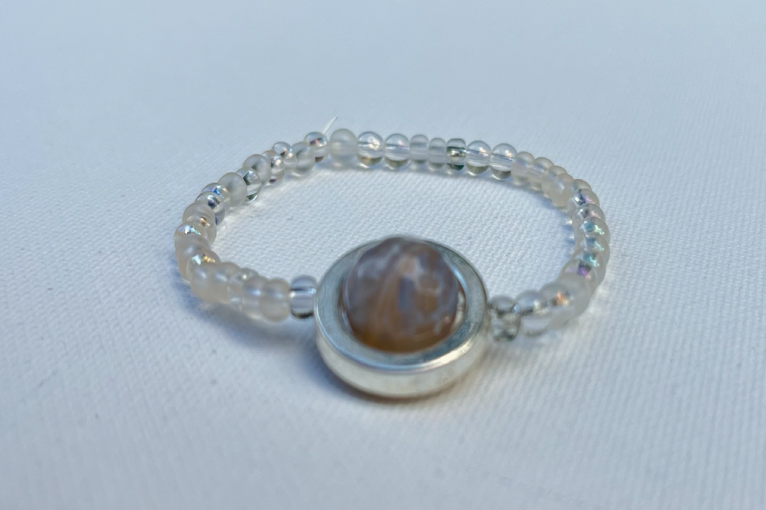 clear small beaded bracelet with silver and grey bead in center
