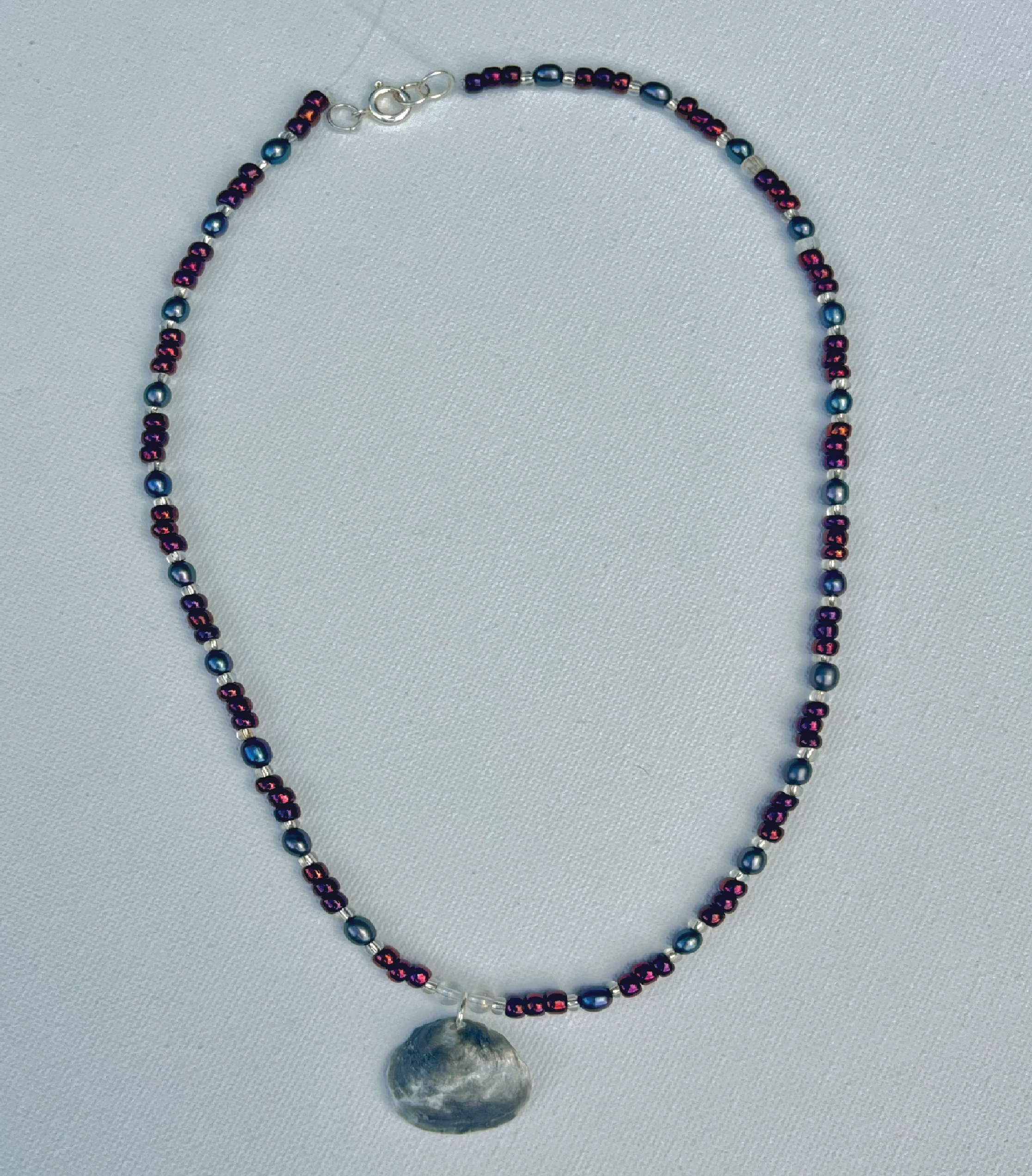 Small dark blue and purple beaded necklace with grey iridescent shell pendant 