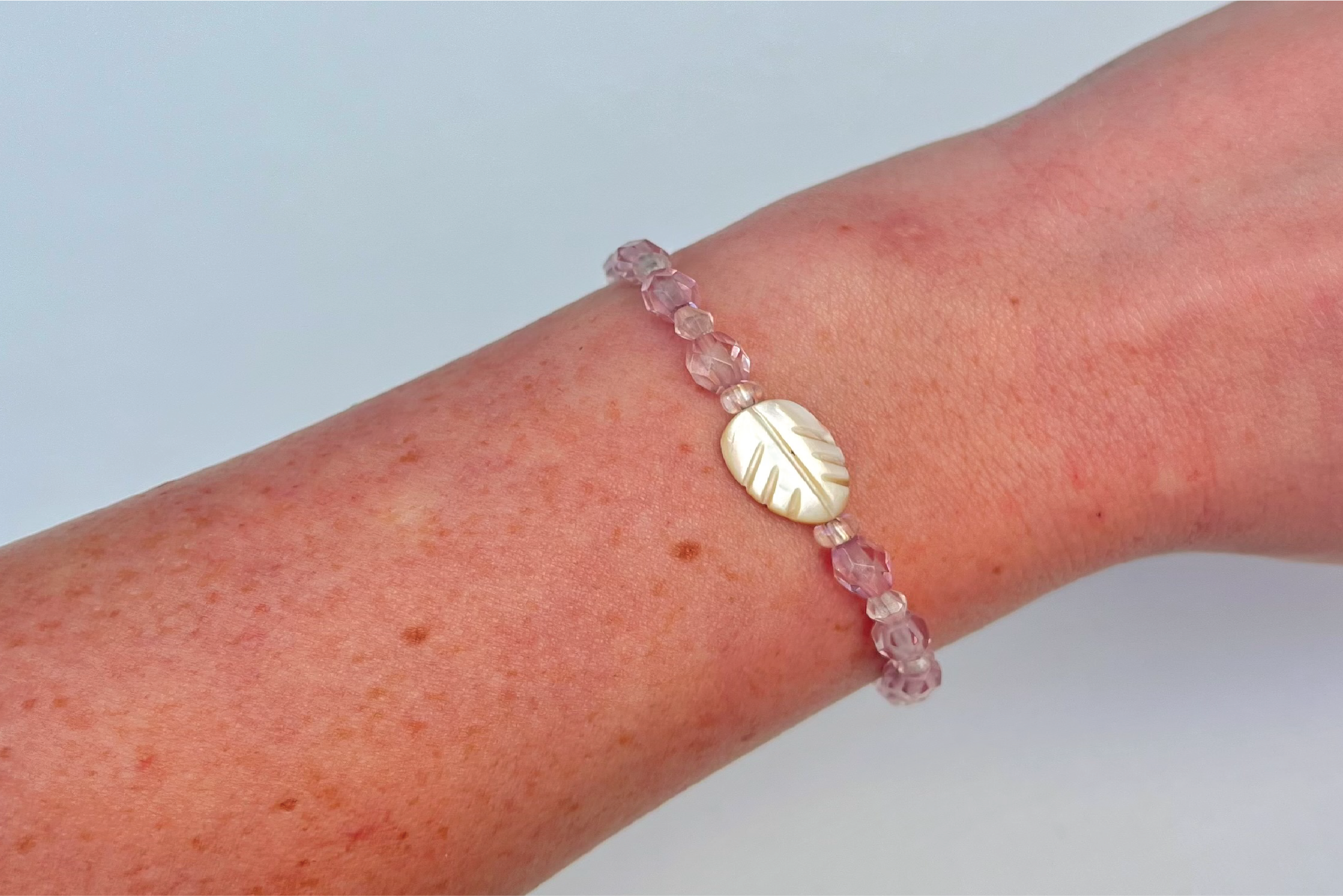 clear pink beaded bracelet with palm leaf in the center