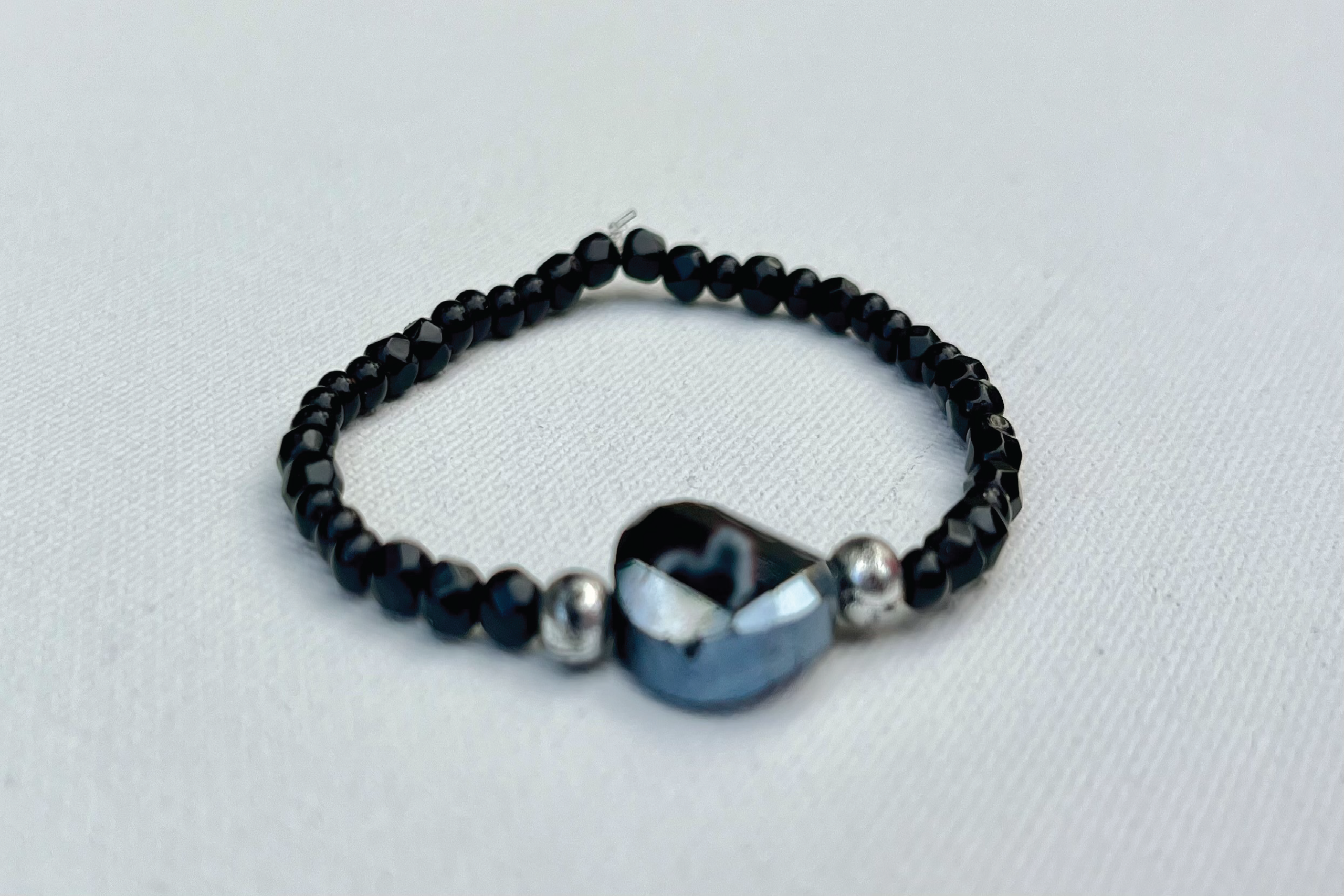 small black and silver beaded bracelet with larger iridescent black bead in center